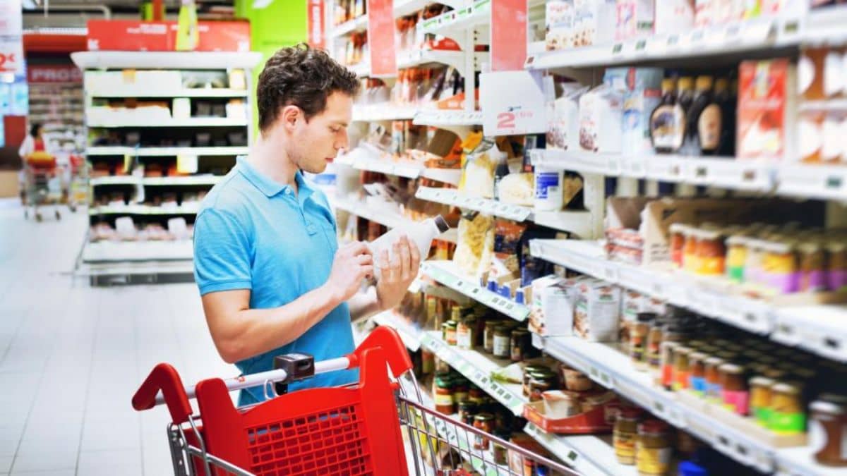 Man examining a product label while shopping in a grocery store aisle.