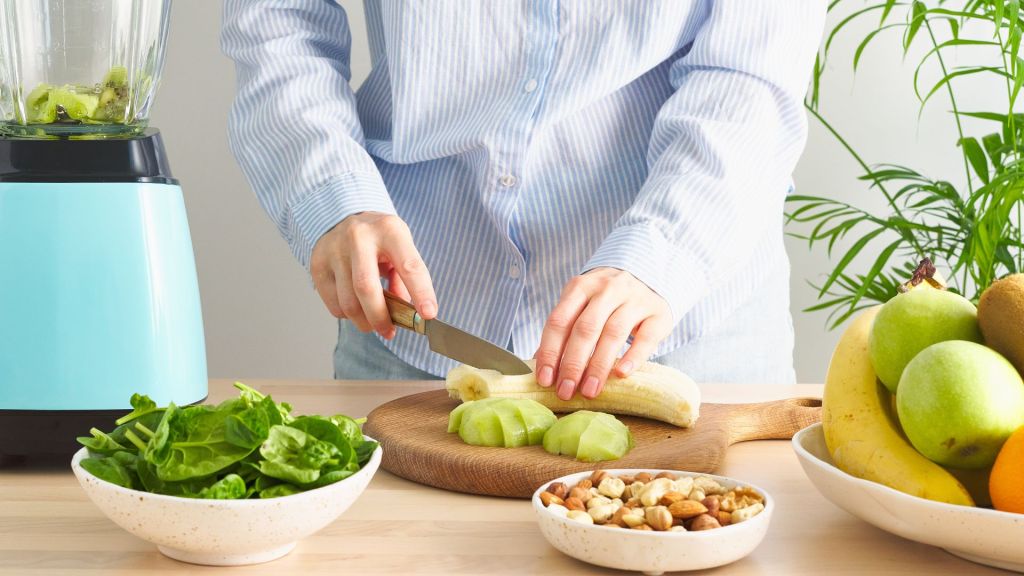 person cutting banana on cutting board in kitchen