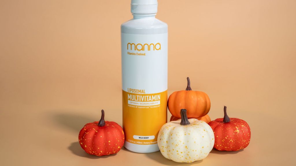 A bottle of liposomal multivitamin surrounded by small decorative pumpkins on a neutral background.