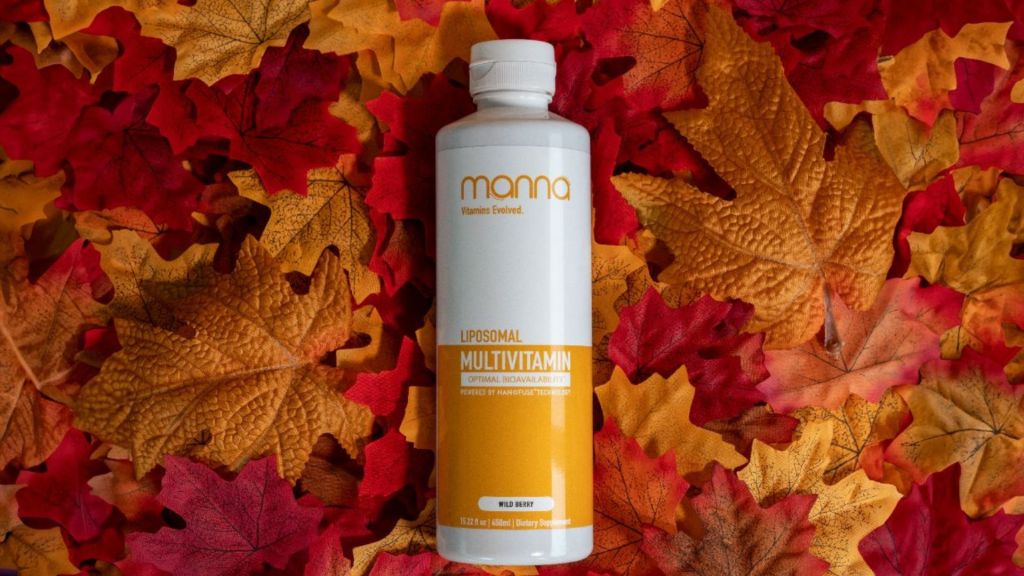A bottle of Mama liposomal multivitamin with wild berry flavor is placed on a background of colorful autumn leaves.
