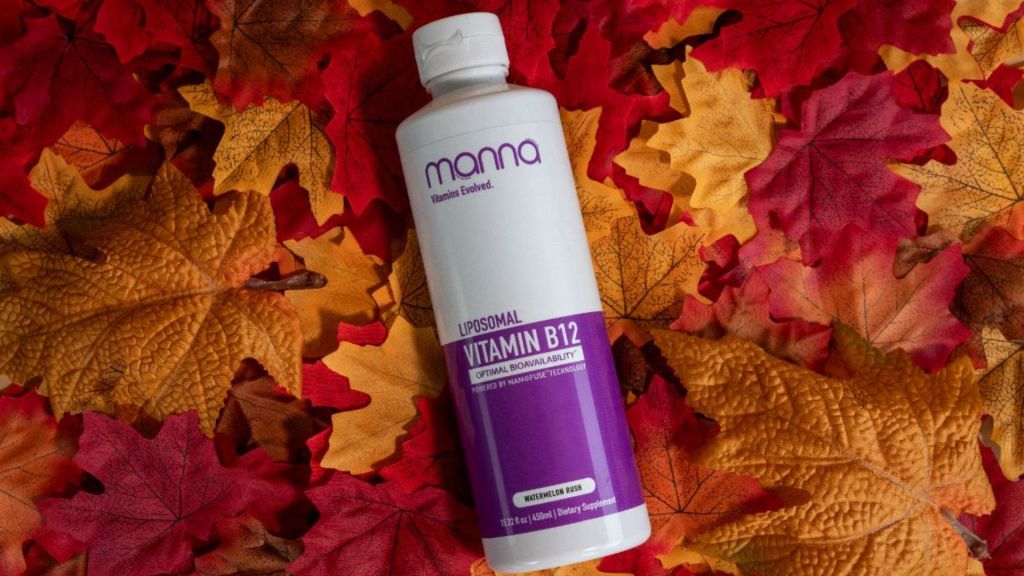 A bottle of Manna Liposomal Vitamin B12 lies on a bed of autumn leaves.
