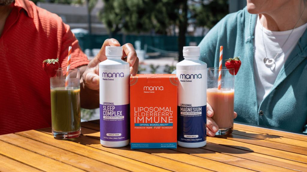 Two people sitting at a wooden table hold drinks while showcasing three Mama brand supplements: Liposomal Sleep Complex, Liposomal Elderberry Immune, and Liposomal Magnesium.