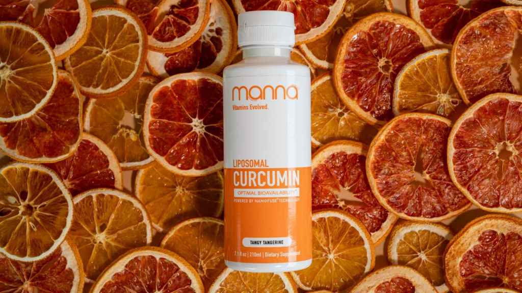 A bottle of Manna Liposomal Curcumin on a background of sliced dried citrus fruits.