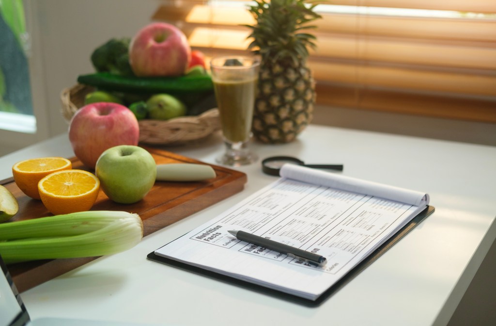 notepad with supplement facts on table with fruits and veggies