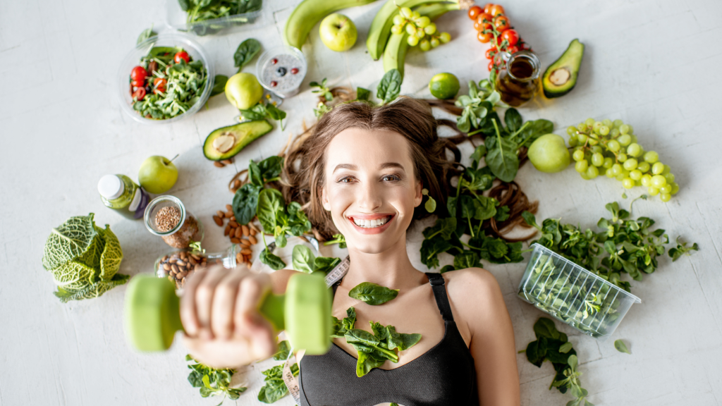 woman laying on floor with fruits and veggies around her while lifting weights