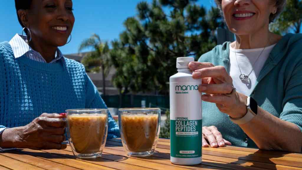 Two people are seated outdoors at a wooden table with two glasses of iced coffee. One of them is holding a bottle labeled "Liposomal Collagen Peptides.