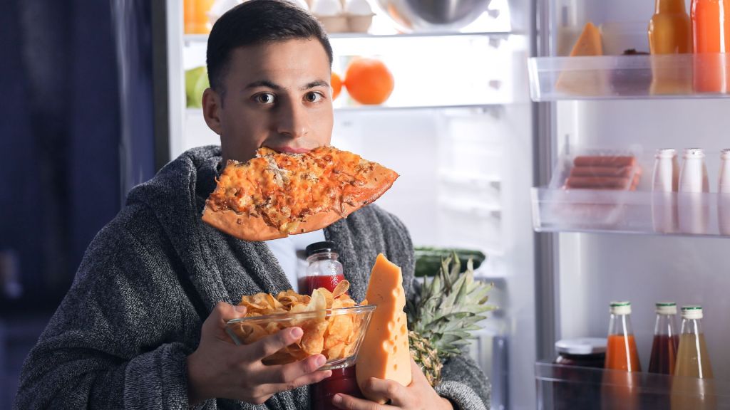 man with pizza, chips, cheese and fruit in his hands.
