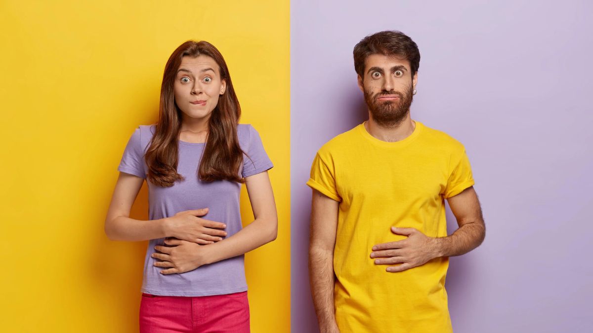 Two people exhibiting puzzled expressions and gesturing towards themselves against a split yellow and purple background.
