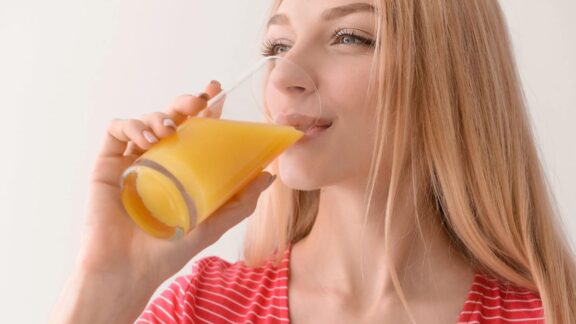 Young woman drinking orange juice from a glass.