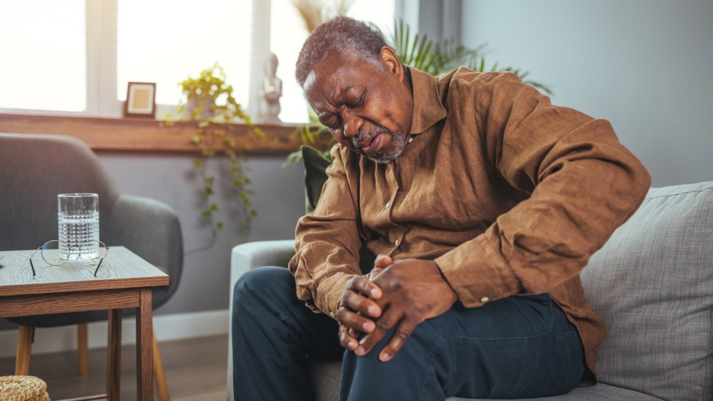 older man holding his knee in pain