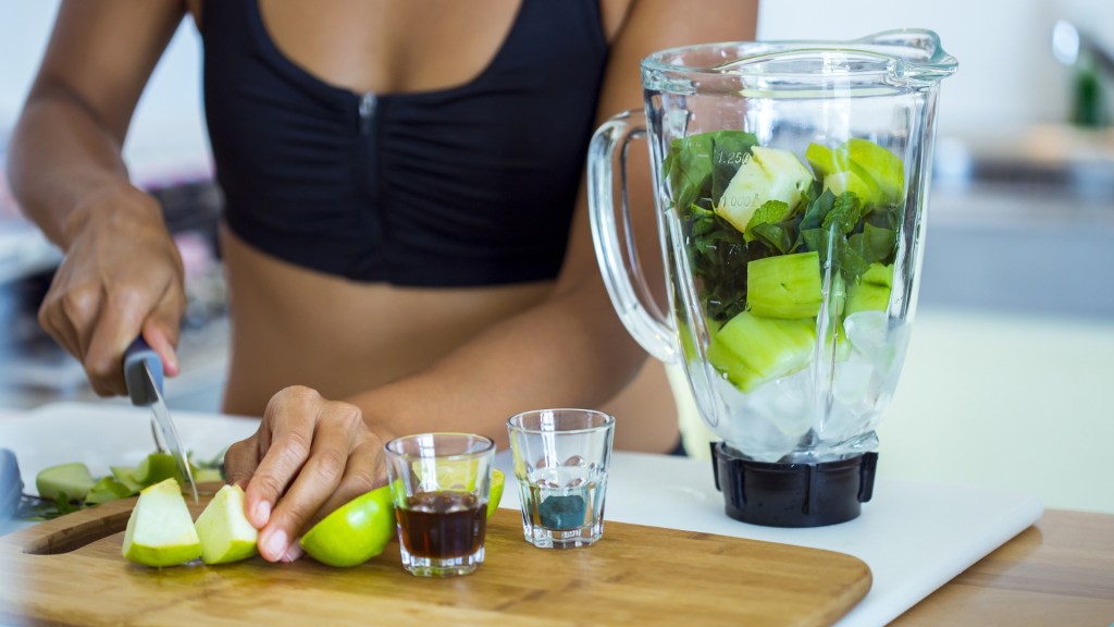 person chipping fruit and putting into a blender