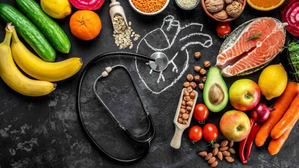 Various healthy foods arranged around a chalk drawing of a heart with a stethoscope, symbolizing heart health and nutrition.