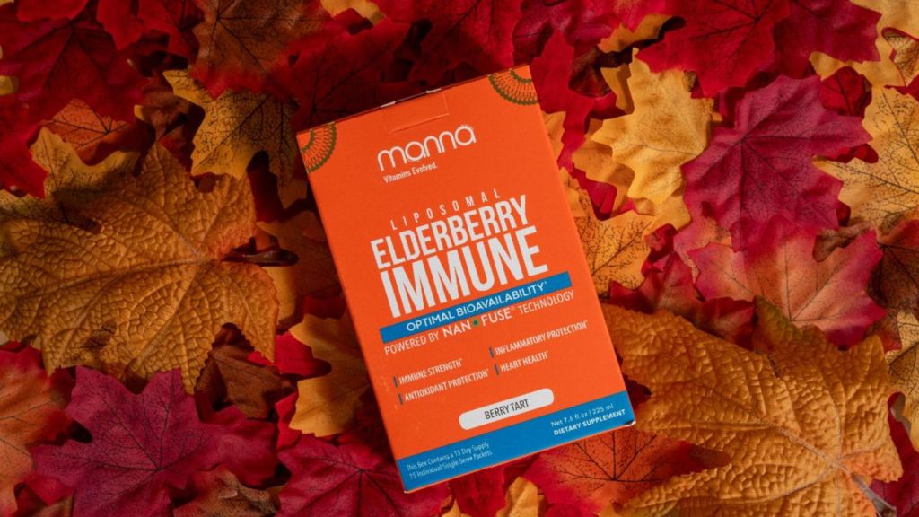 A box labeled "Liposomal Elderberry Immune" lies on a surface covered with autumn leaves. The box highlights benefits like immune strengthening and cardiovascular protection.