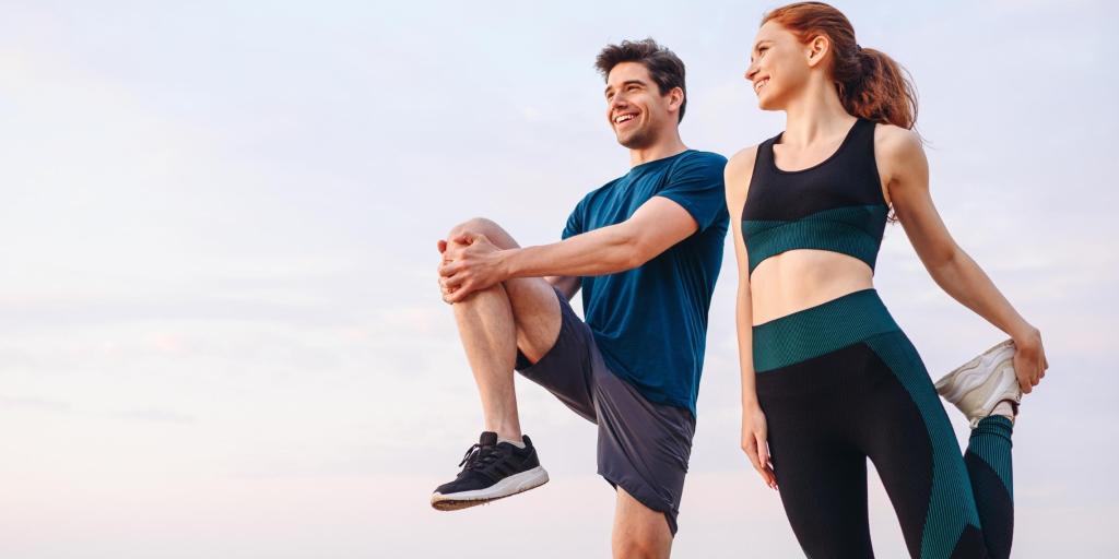 man and woman stretching in athletic clothing