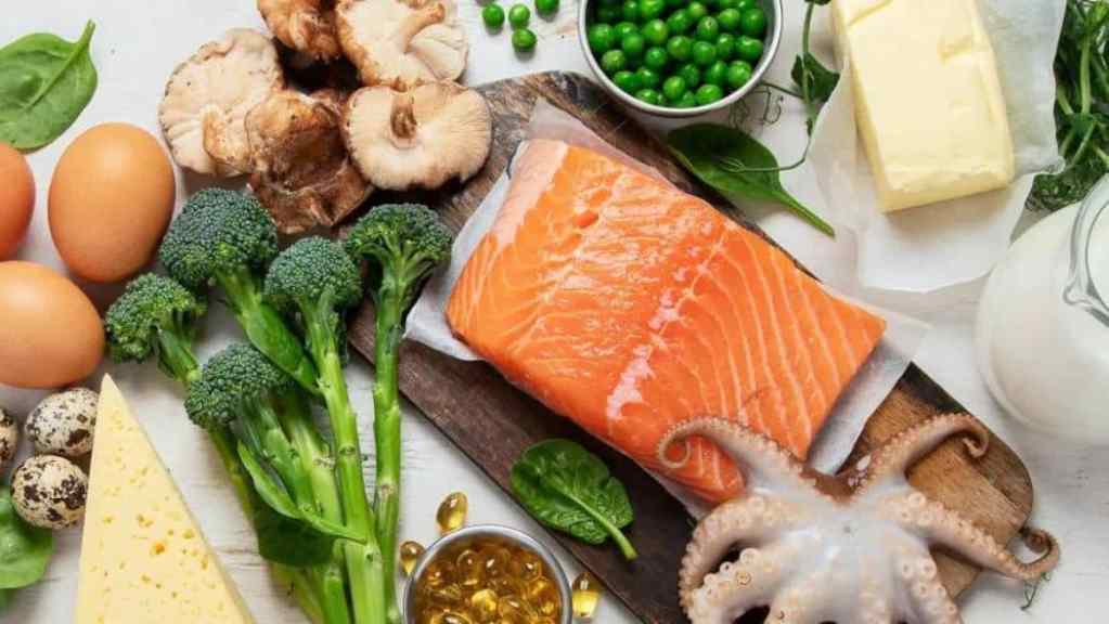 Various fresh foods including salmon, vegetables, dairy, and eggs on a white surface.