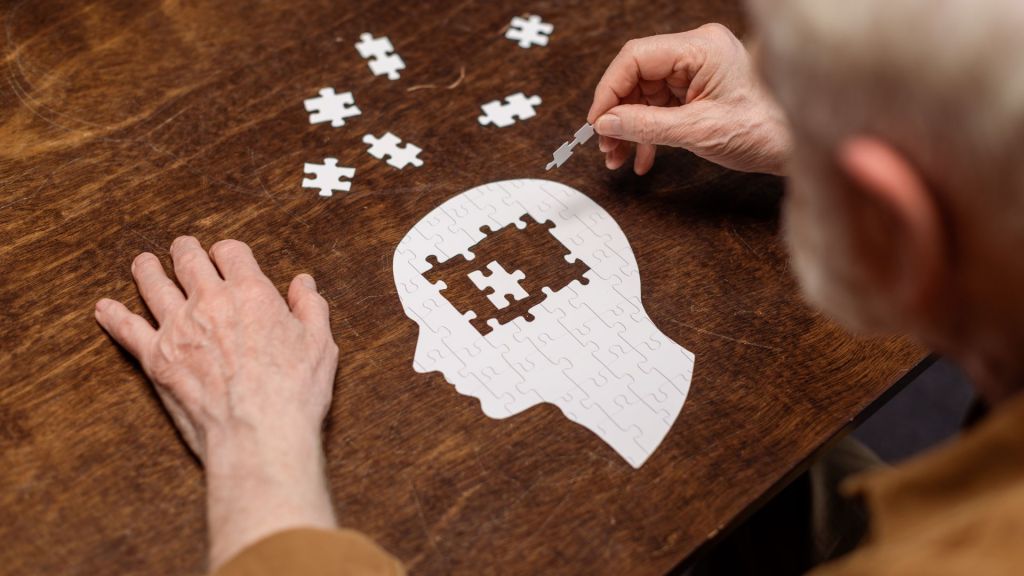 person doing a puzzle that has the shape of a persons head