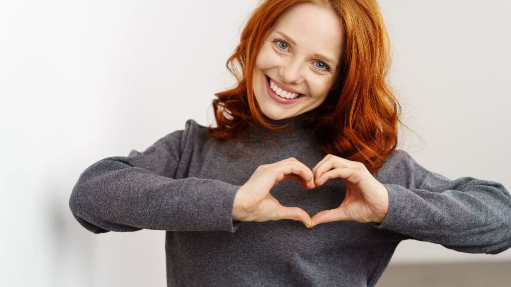woman with her hands making a heart smiling