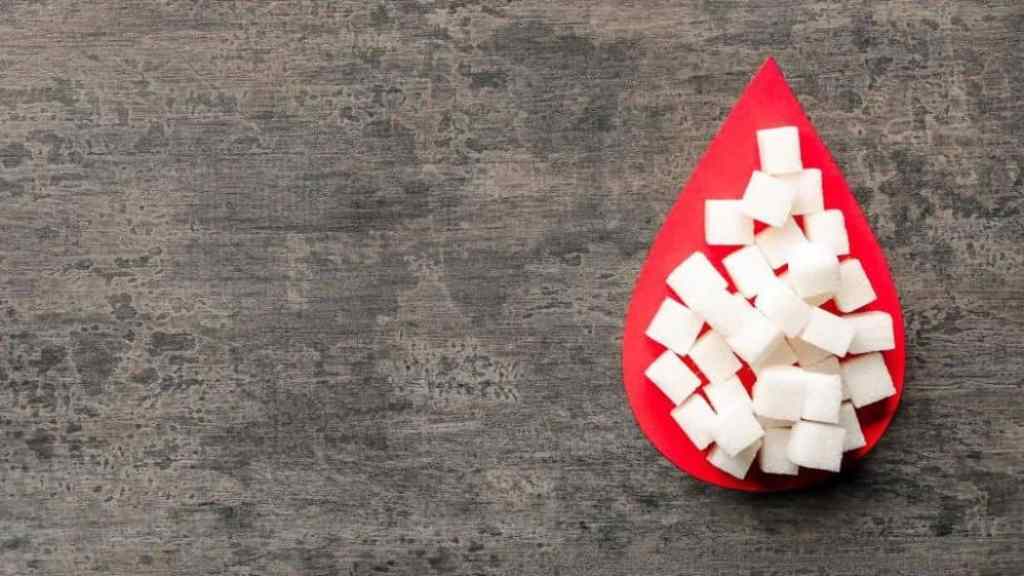 Sugar cubes stacked on a red napkin shaped like a blood droplet on a textured grey surface.