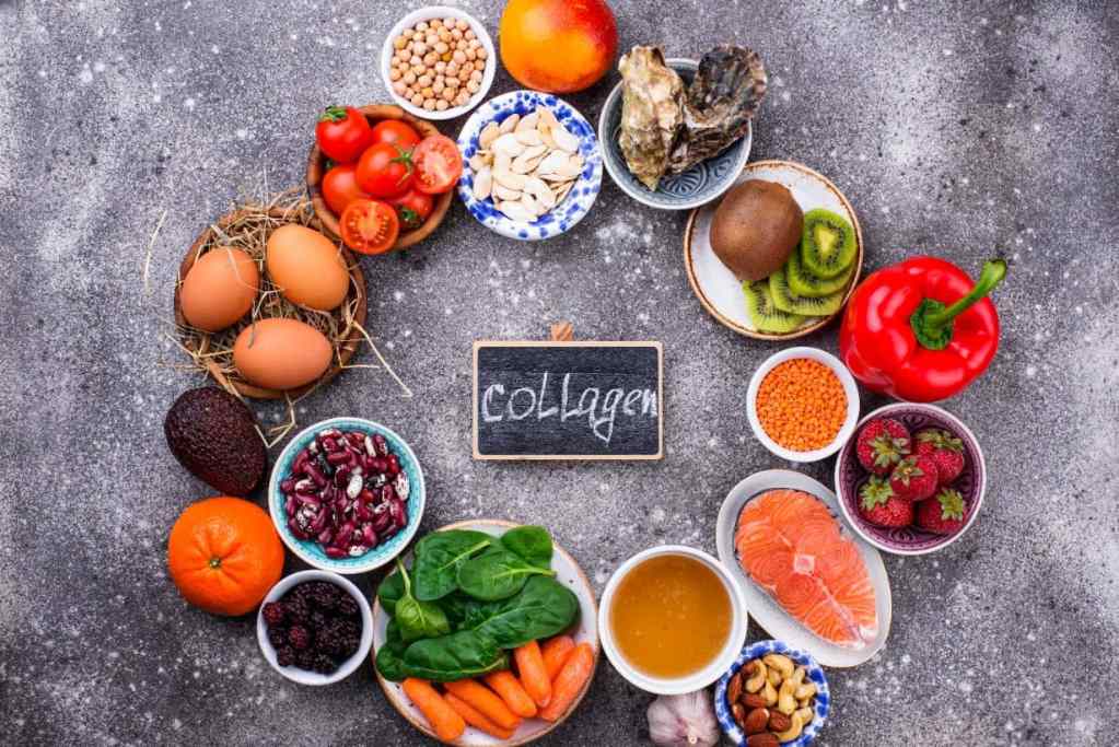A variety of foods rich in collagen surround a small blackboard with "collagen" written on it. Items include eggs, nuts, salmon, berries, beans, and vegetables.