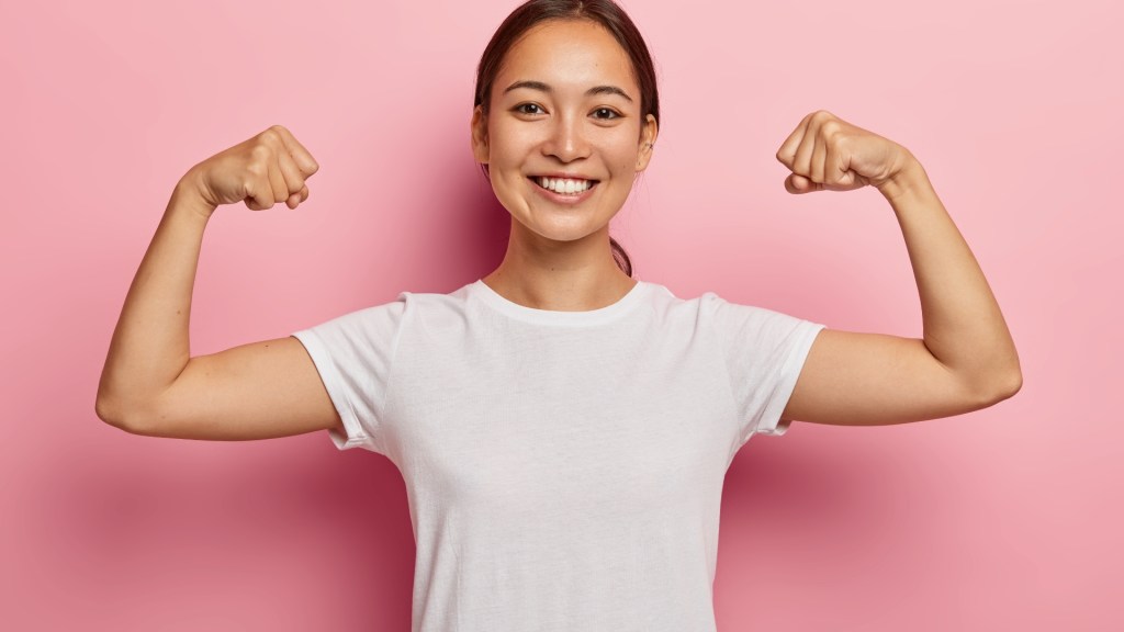 Woman flexing her arms against a pink background