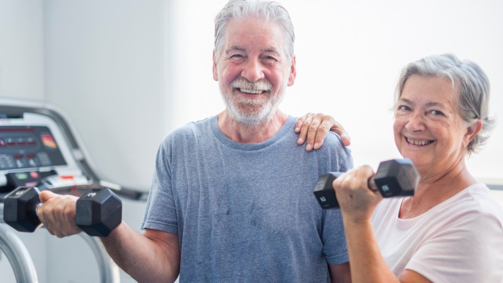Older couple smiling and holding dumbbells