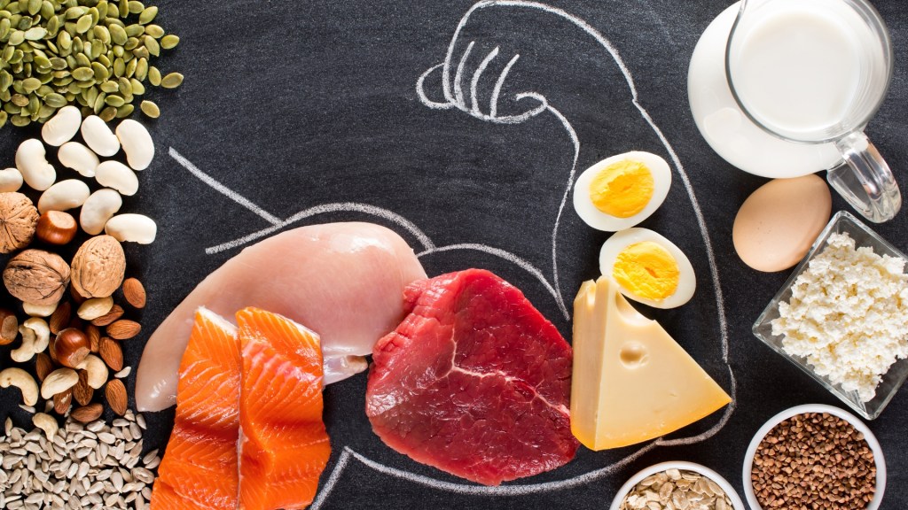 Protein dense foods on a chalkboard, arranged inside a drawing of someone flexing their arm.