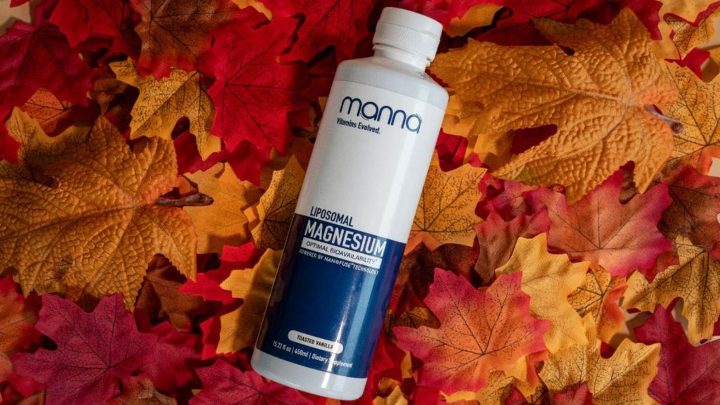 A bottle of Manna Liposomal Magnesium lies on a bed of colorful autumn leaves.
