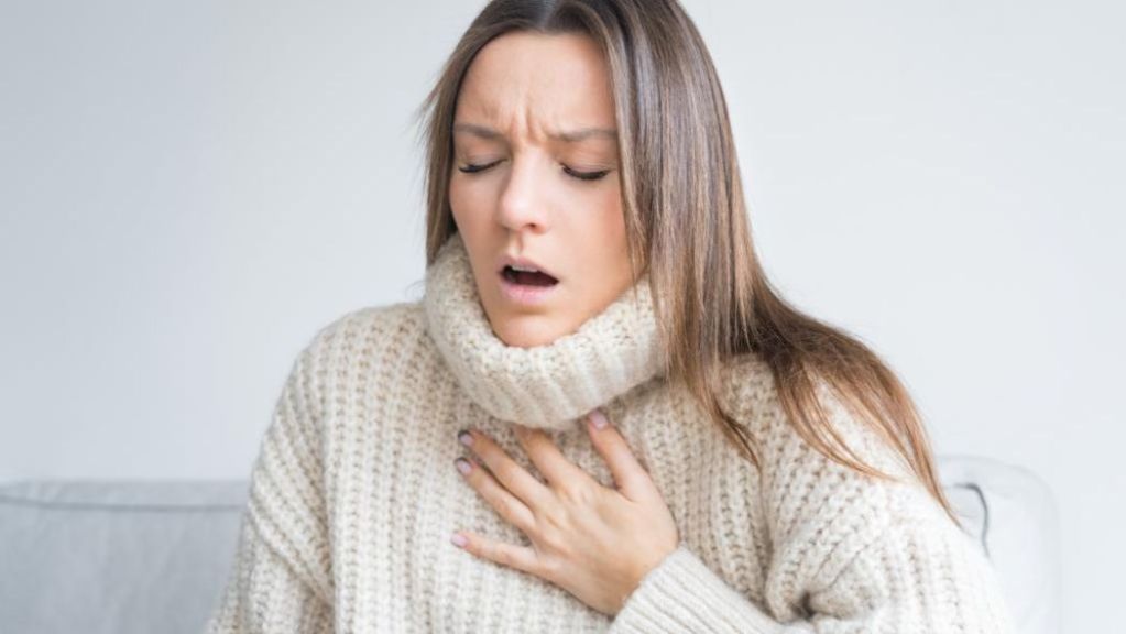 Woman coughing and appearing to be unwell.