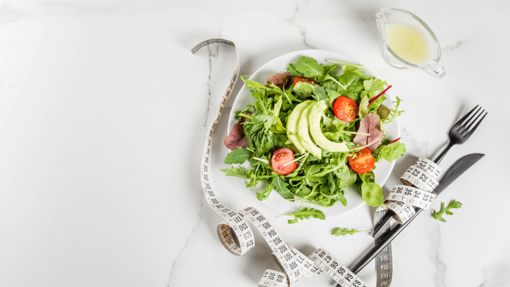 Salad with a tape measurer wrapped around a fork and knife