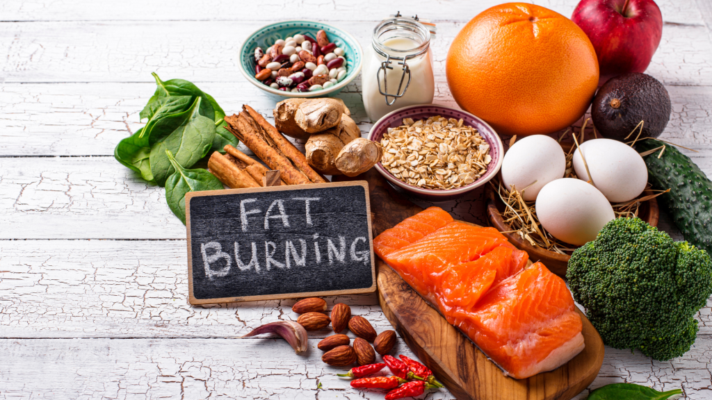 fat burning written on a chalkboard surrounded by foods (salmon, nuts, peppers, eggs)