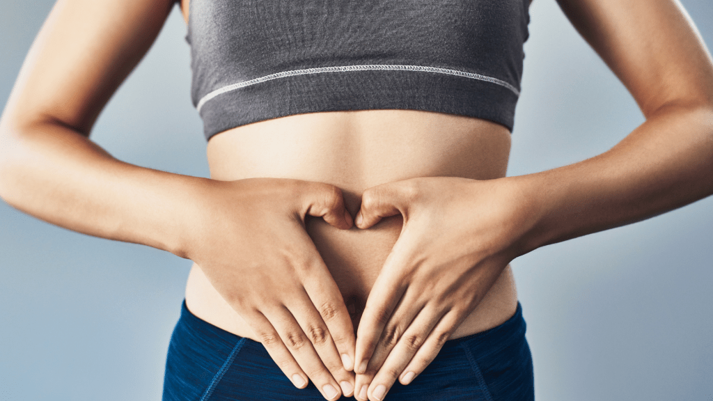 person with hands making a heart over stomach