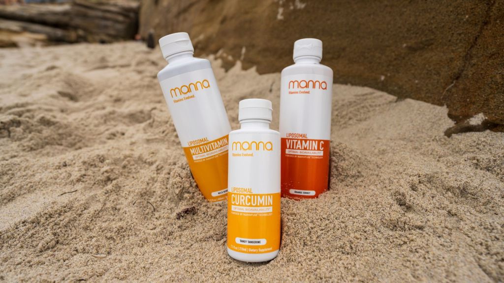 Three bottles of Mama vitamins, including Multivitamin, Vitamin C, and Curcumin, are placed on sandy ground near a rock.