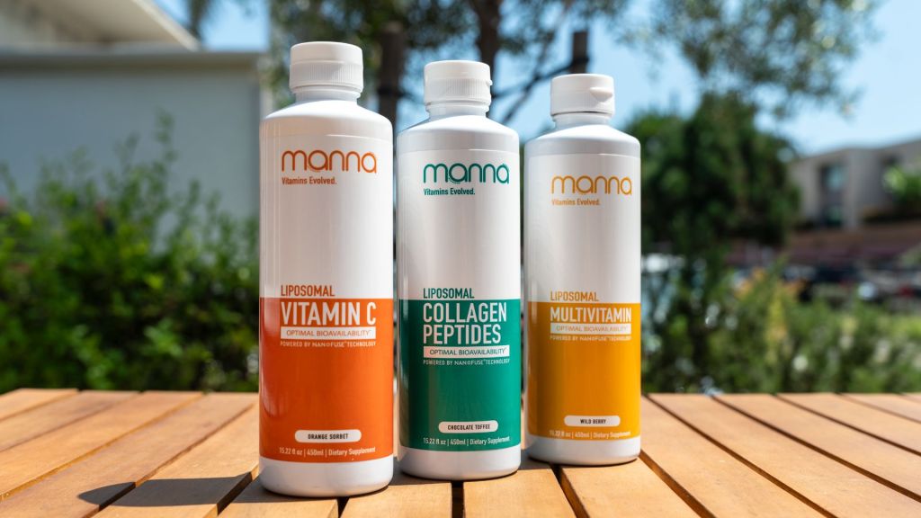 Three bottles of Mama brand vitamins and supplements are placed on a wooden table outdoors.