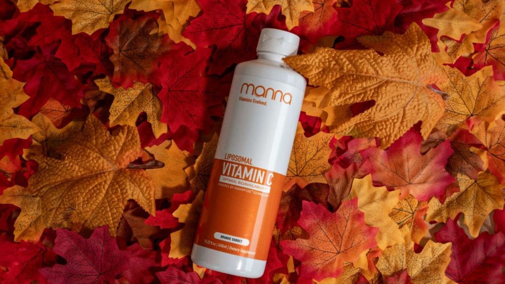 A bottle of liposomal vitamin C lies on a bed of colorful autumn leaves.