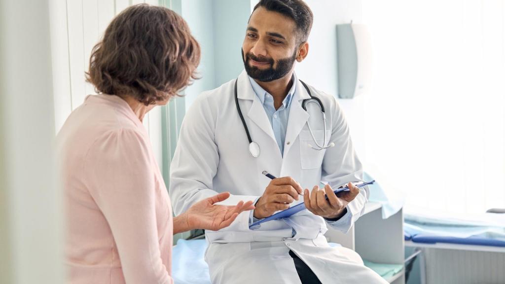 A woman talking to her doctor while he takes notes on a clipboard.