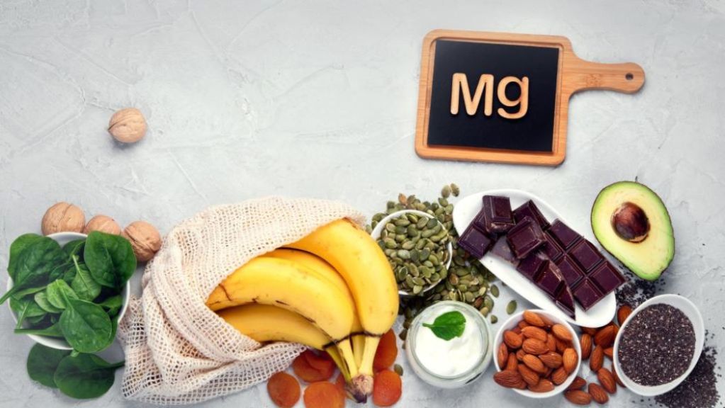 Variety of magnesium rich foods along with a chalk board with "Mg" written on it