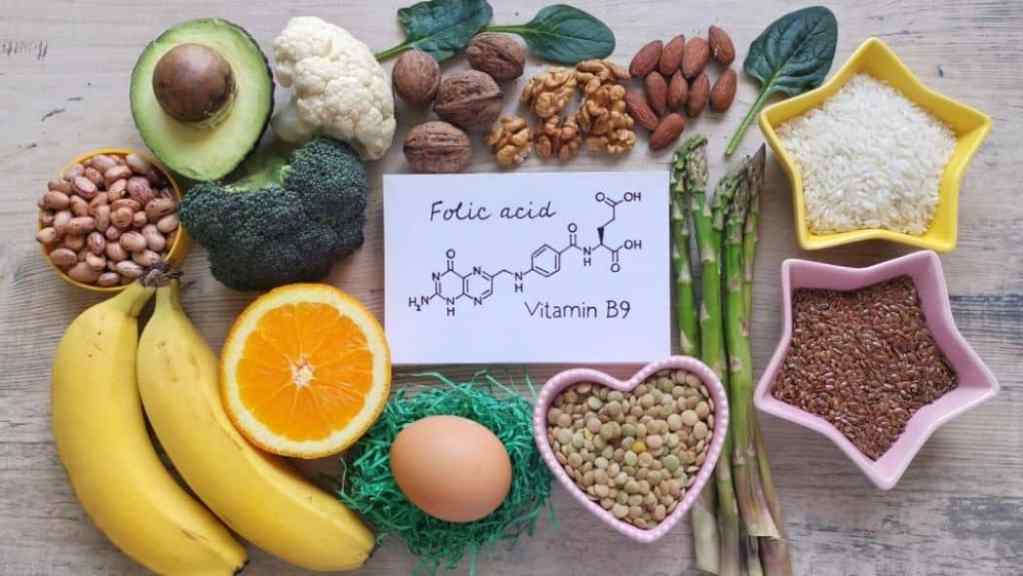 Variety of foods rich in folic acid. In the center is a card with "folic acid" and the chemical symbol written on it.