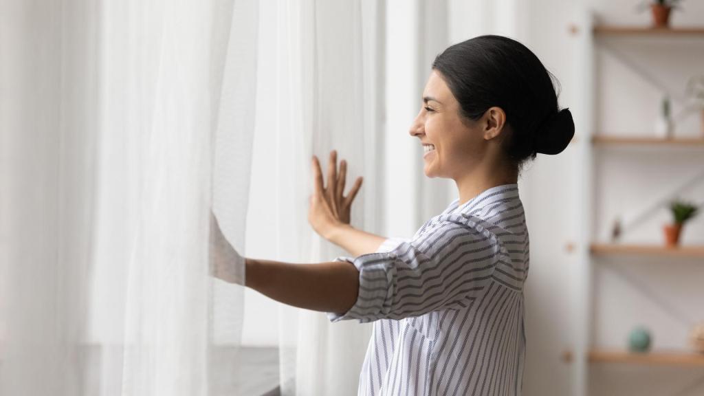 woman opening curtains and smiling
