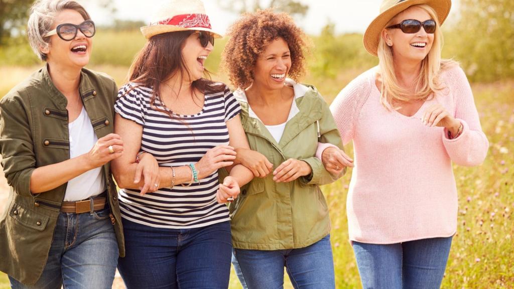 4 woman walking together outdoors with arms interlocked