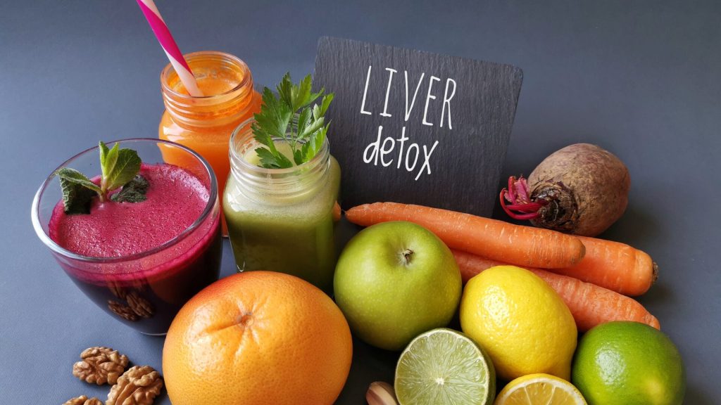 Variety of colorful detox smoothies with fresh fruits, vegetables, and a sign reading "liver detox.