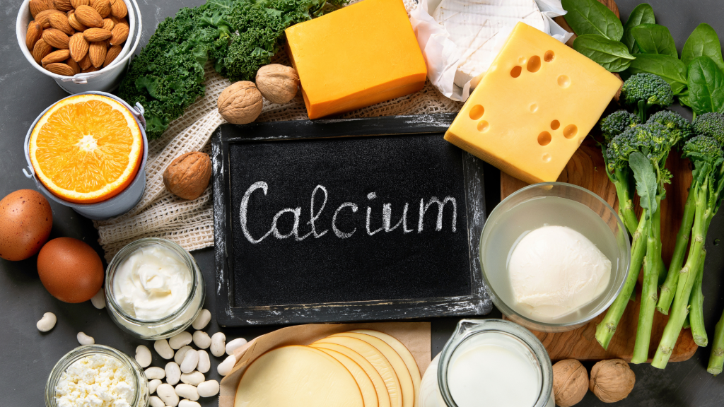 Calcium written on chalkboard with food sources of it including cheese, broccoli, nuts, eggs and more.