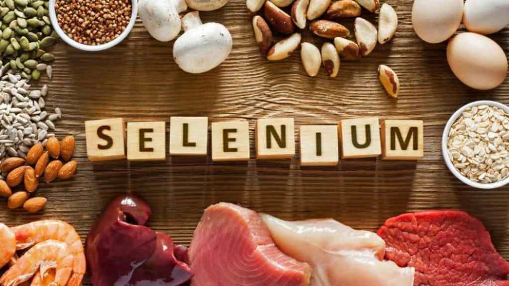 Various foods rich in selenium with the word "selenium" spelled out in wooden blocks on a table.