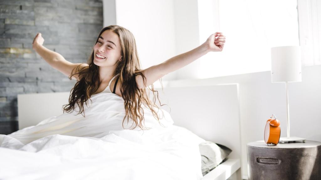 woman stretching while sitting up in bed