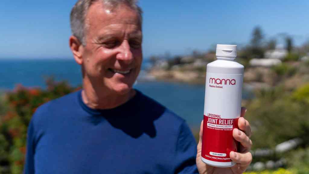 Man holding a bottle labeled "Liposomal Joint Relief" with a coastal background.