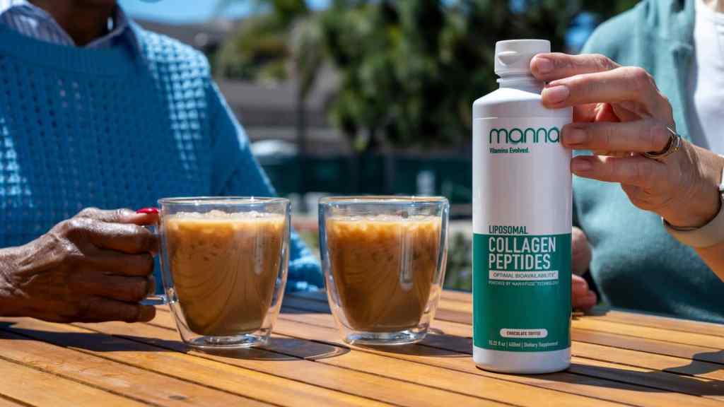 Two people seated outdoors with frothy drinks in glasses, one holding a bottle of "Mama Liposomal Collagen Peptides Supplement." Palm trees and a building are visible in the background.