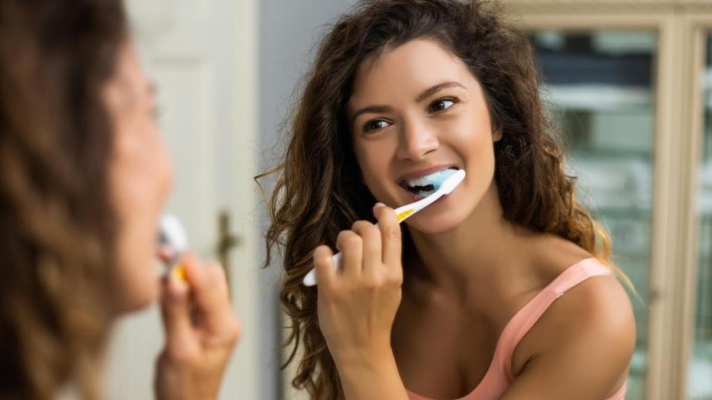 Woman brushing her teeth in the mirror