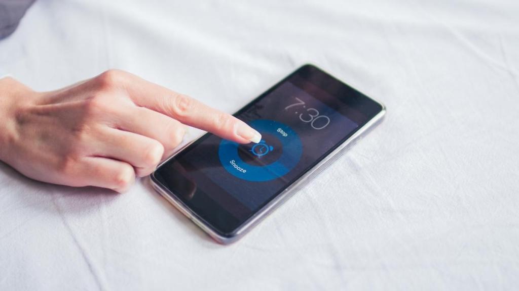Alarm on a smartphone ringing, with a finger reaching to turn it off
