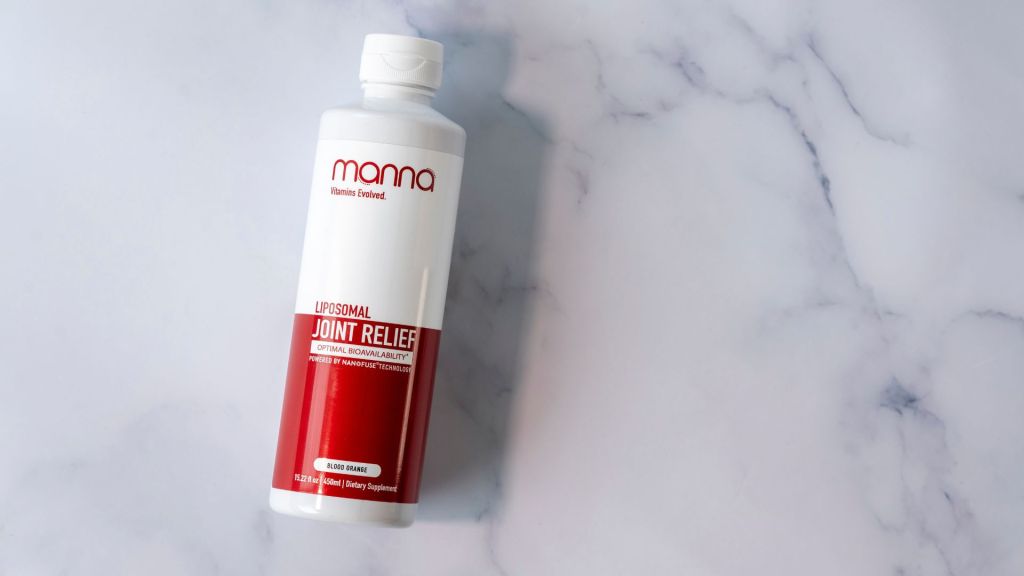 A white and red bottle labeled "Liposomal Joint Relief" from Manna is placed on a white marble surface.