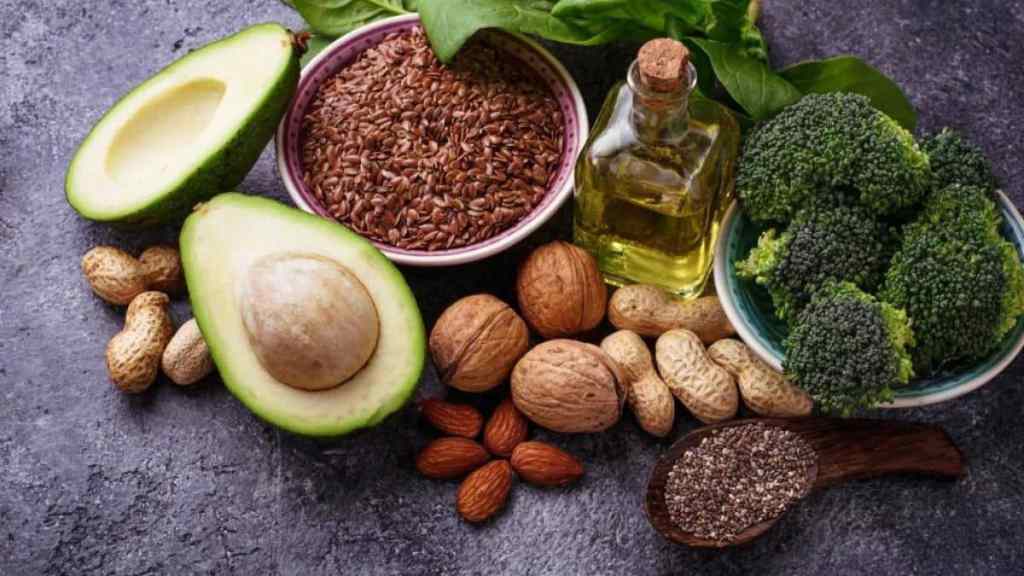 Assortment of healthy foods rich in essential fats, including nuts, seeds, avocado, and oil.