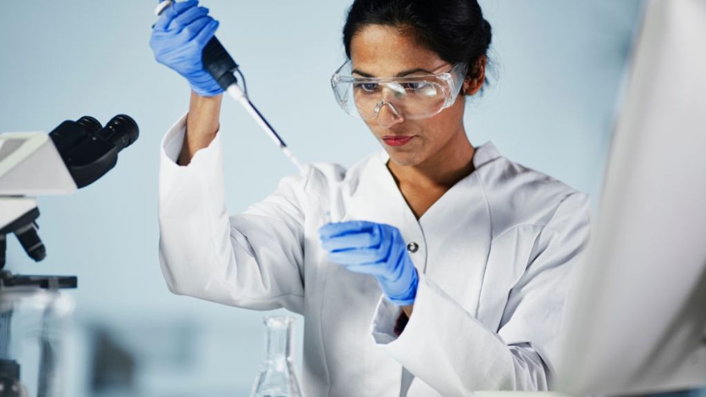 Scientist using a pipette to transfer liquid to a test tube in a laboratory setting.